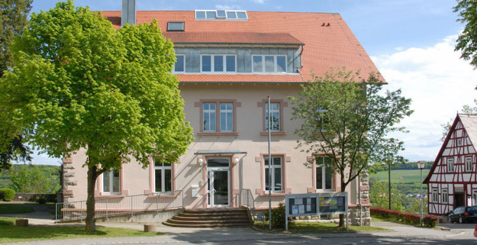 Das Rathaus von Krautheim in Baden-Württemberg. Links ein Baum in hellgrünem Frühlings-Laub. Rechts sieht man Fachwerk. Krautheim ist Sitz der Firma Rüdinger.